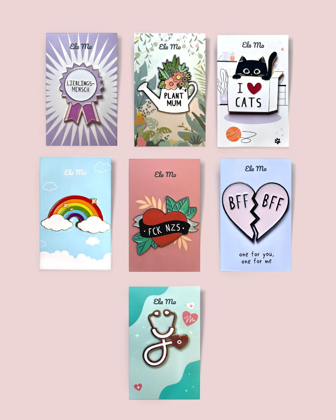 Ela Mo™ Pin für Rucksäcke| Rainbow. Verschiedene Ausführungen von Rucksackpins auf rosa Hintergrund.