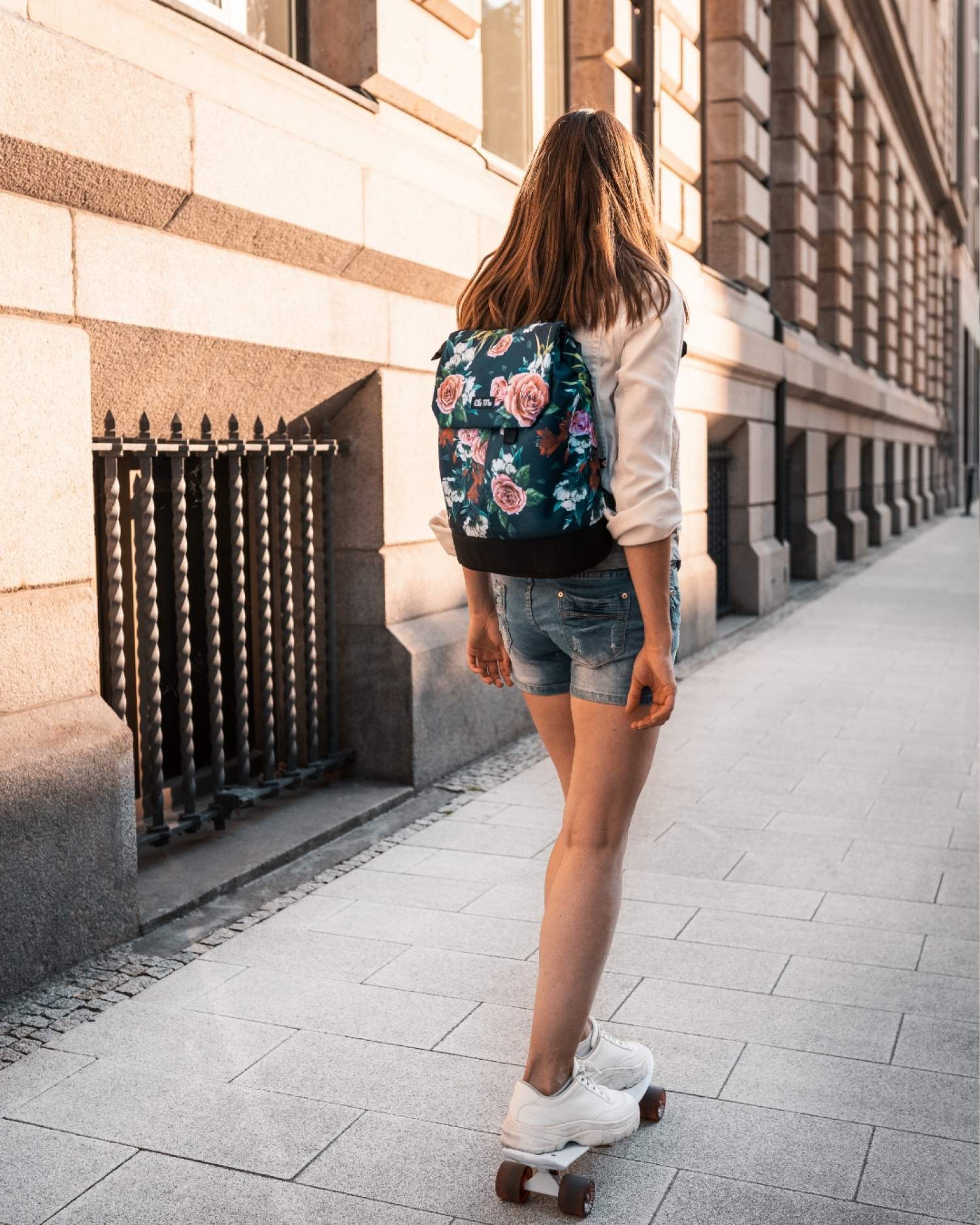 Ela Mo™ Daypack Rucksack | A Rose. Eine Frau mit dem Rucksack auf dem Rücken im Freien – alltäglicher Lifestyle.