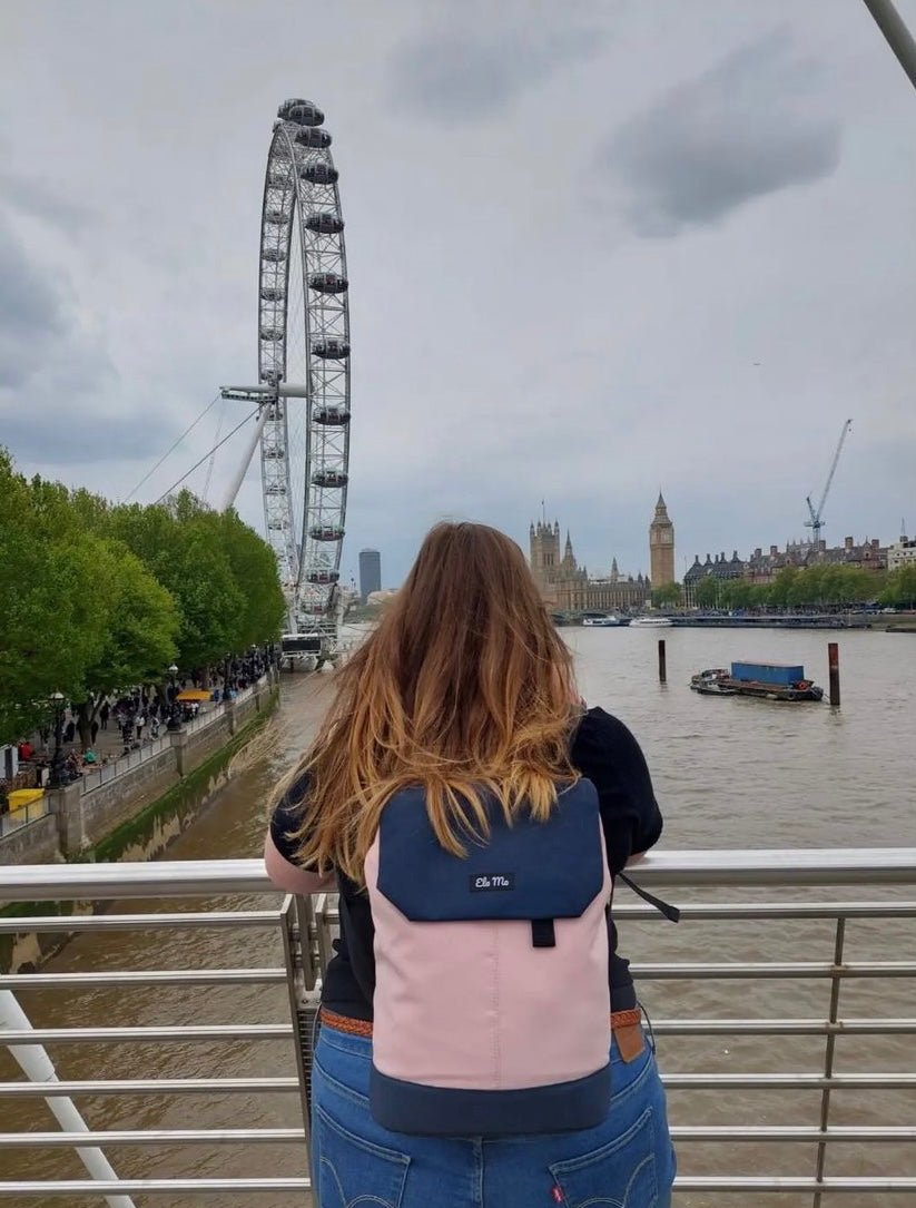 Ela Mo™ Daypack Rucksack | Pink & Blue. Eine Frau mit dem Rucksack auf dem Rücken im Freien.