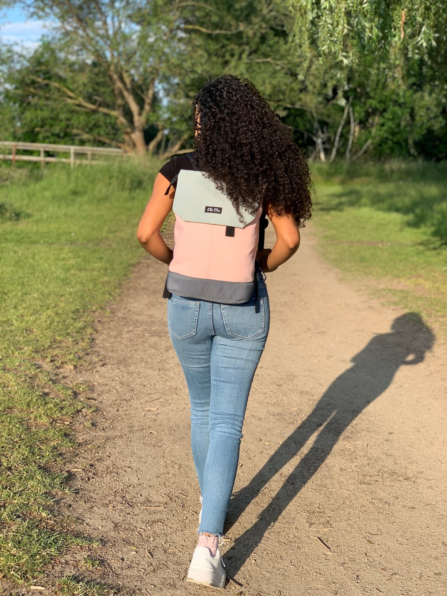 Ela Mo™ Daypack Rucksack | Rose on Rocks. Eine Frau mit dem Rucksack auf dem Rücken im Freien – alltäglicher Lifestyle.