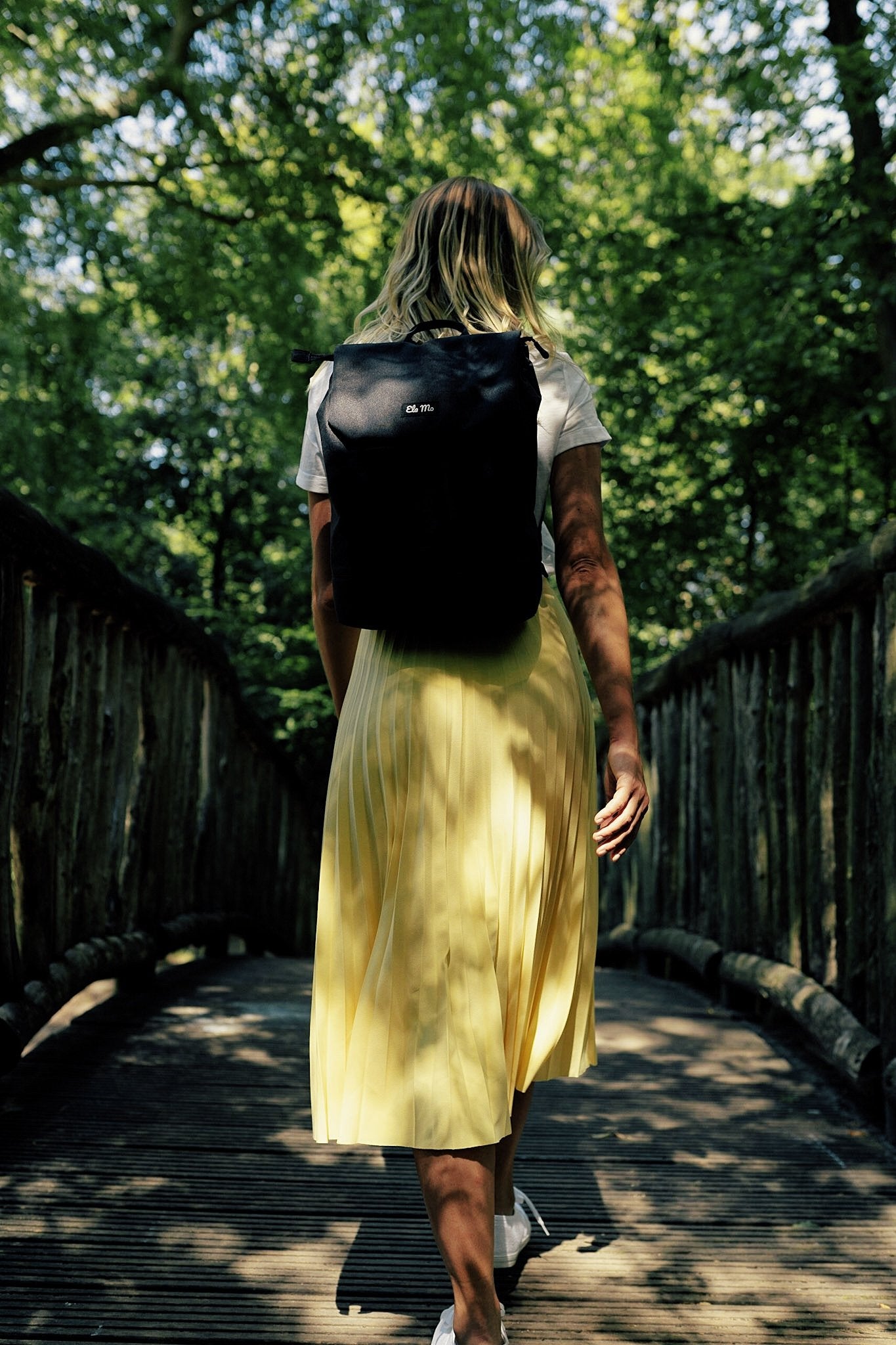 Ela Mo™ Daypack Rucksack | Stone. Eine Frau mit dem Rucksack auf dem Rücken im Freien – alltäglicher Lifestyle.