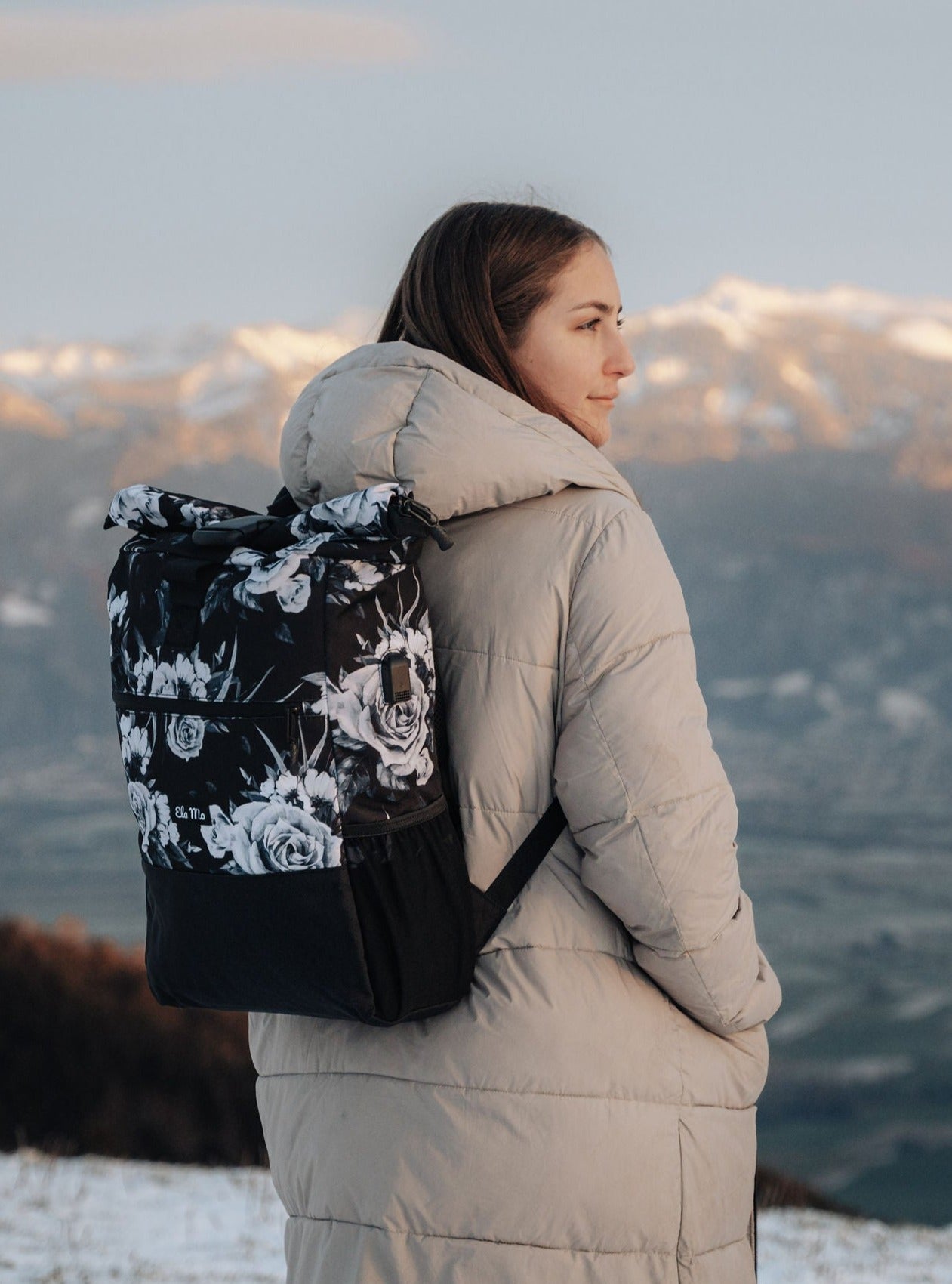 Ela Mo™ Rolltop Rucksack | Nightrose. Eine Frau mit dem Rucksack auf dem Rücken im Freien.