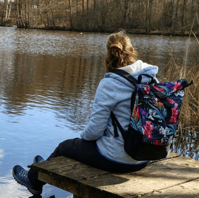 Ela Mo™ Rolltop Rucksack | Tropical Heat. Eine Frau mit dem Rucksack auf dem Rücken – alltäglicher Lifestyle.