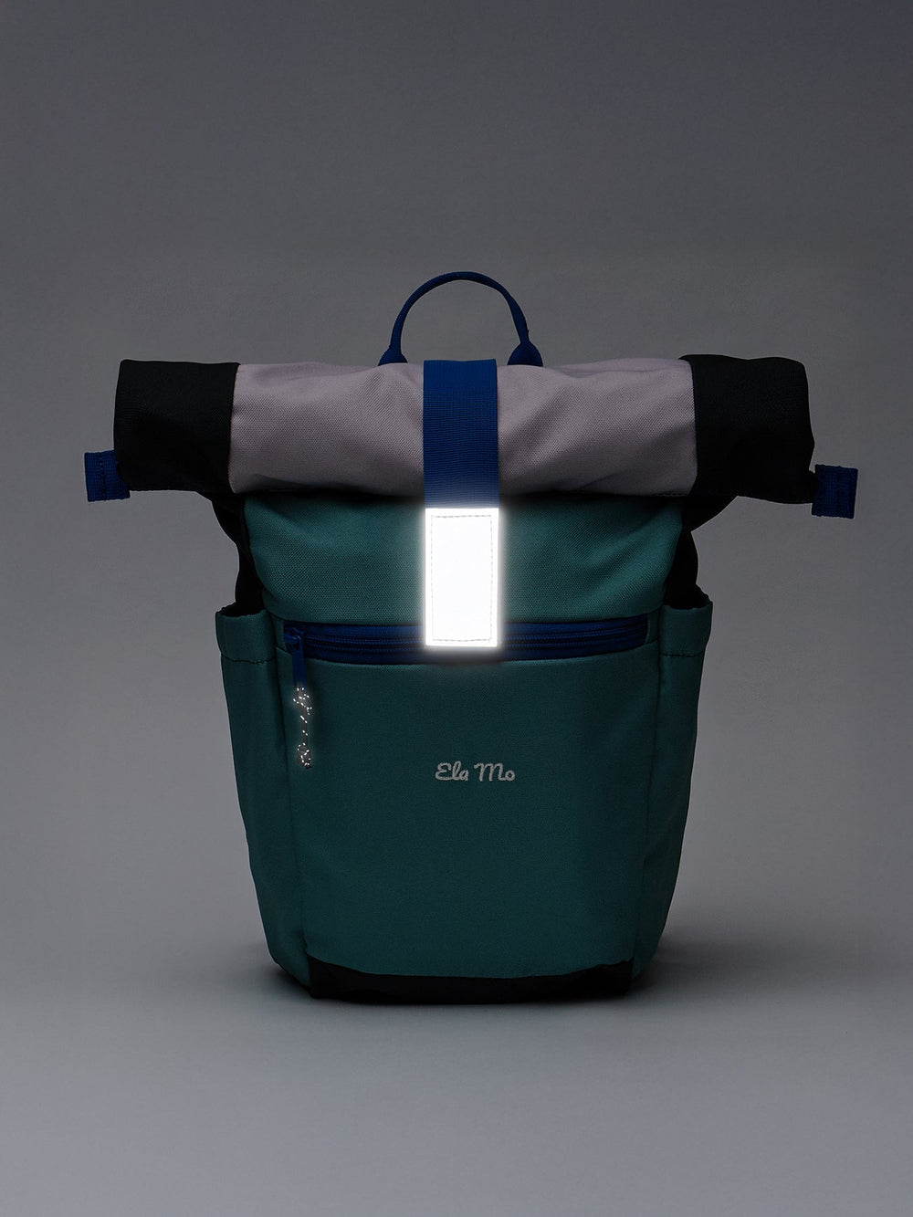 Ela Mo™ Kinderrucksack (6-10 Jahre) | Blue Mint. Ein blauer Rucksack im Dunkeln mit reflektierendem Verschluss.