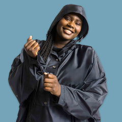 Ela Mo™ Regenponcho | Black. Eine Frau mit Regenponcho und Kapuze auf dem Kopf.