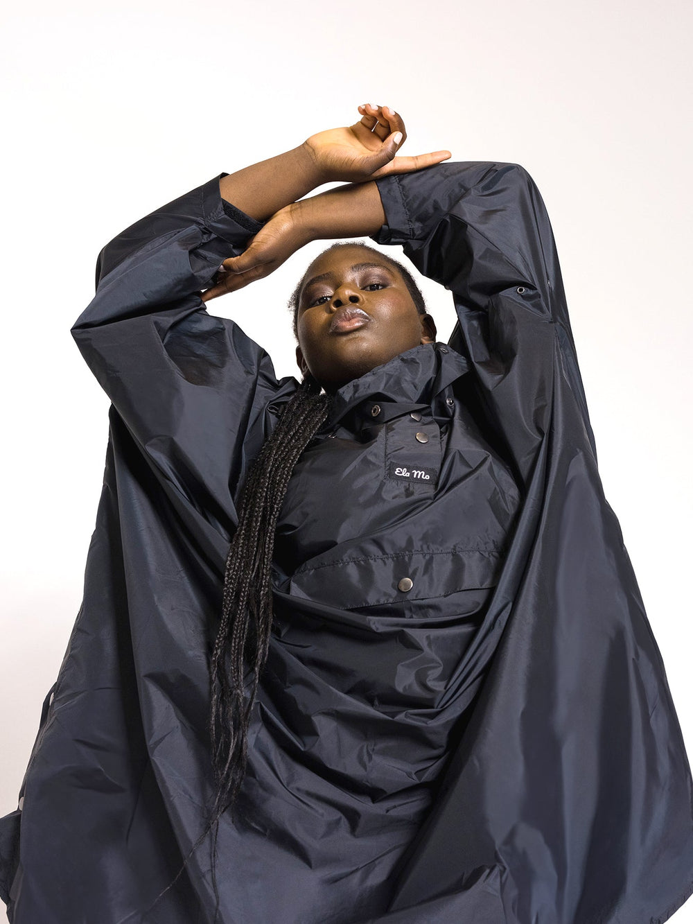 Ela Mo™ Regenponcho | Black. Frau mit blauem Regenponcho auf weißem Hintergrund.
