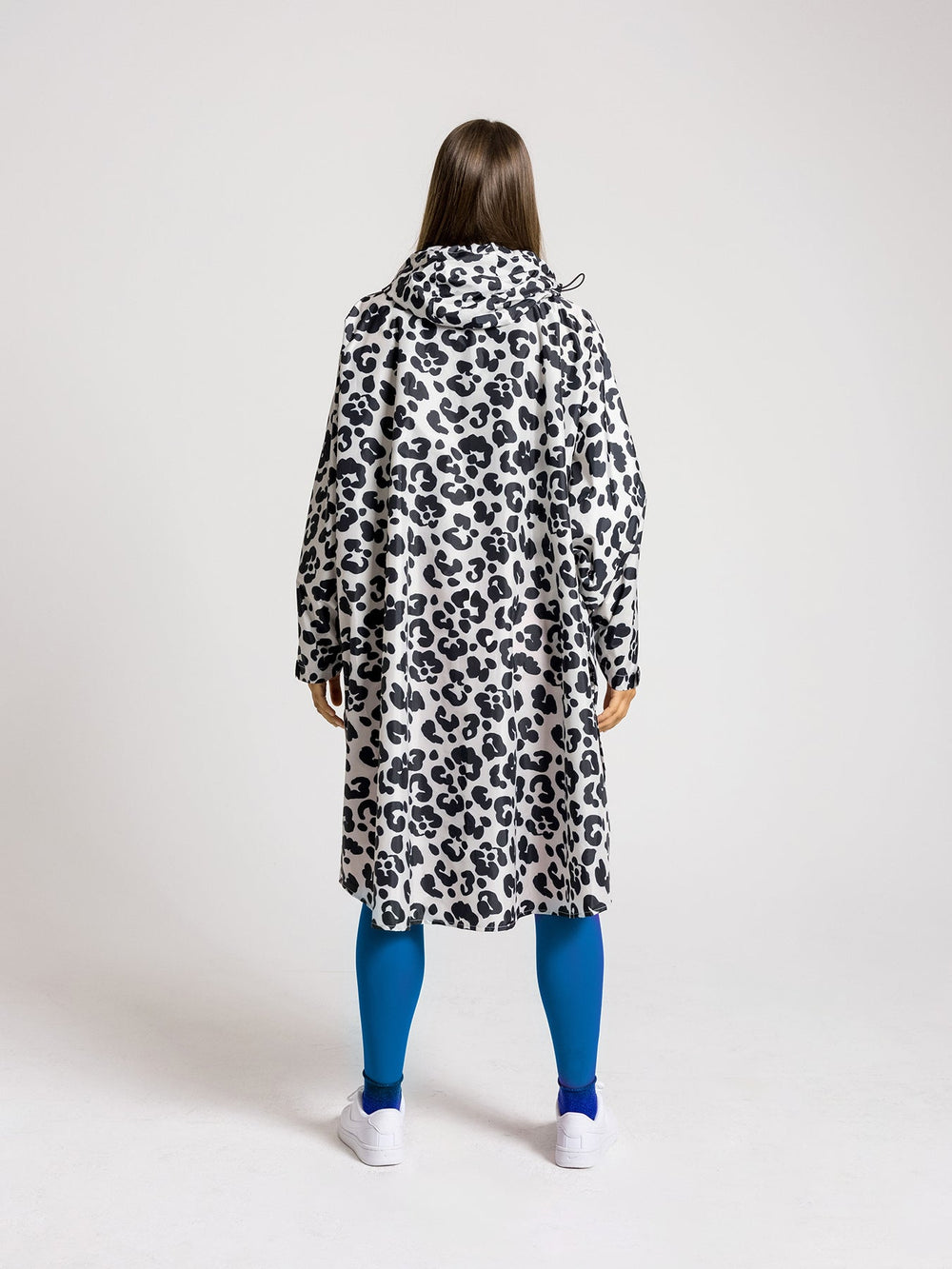 Ela Mo™ Regenponcho | Leo. Frau mit Regenponcho von hinten auf weißem Hintergrund.