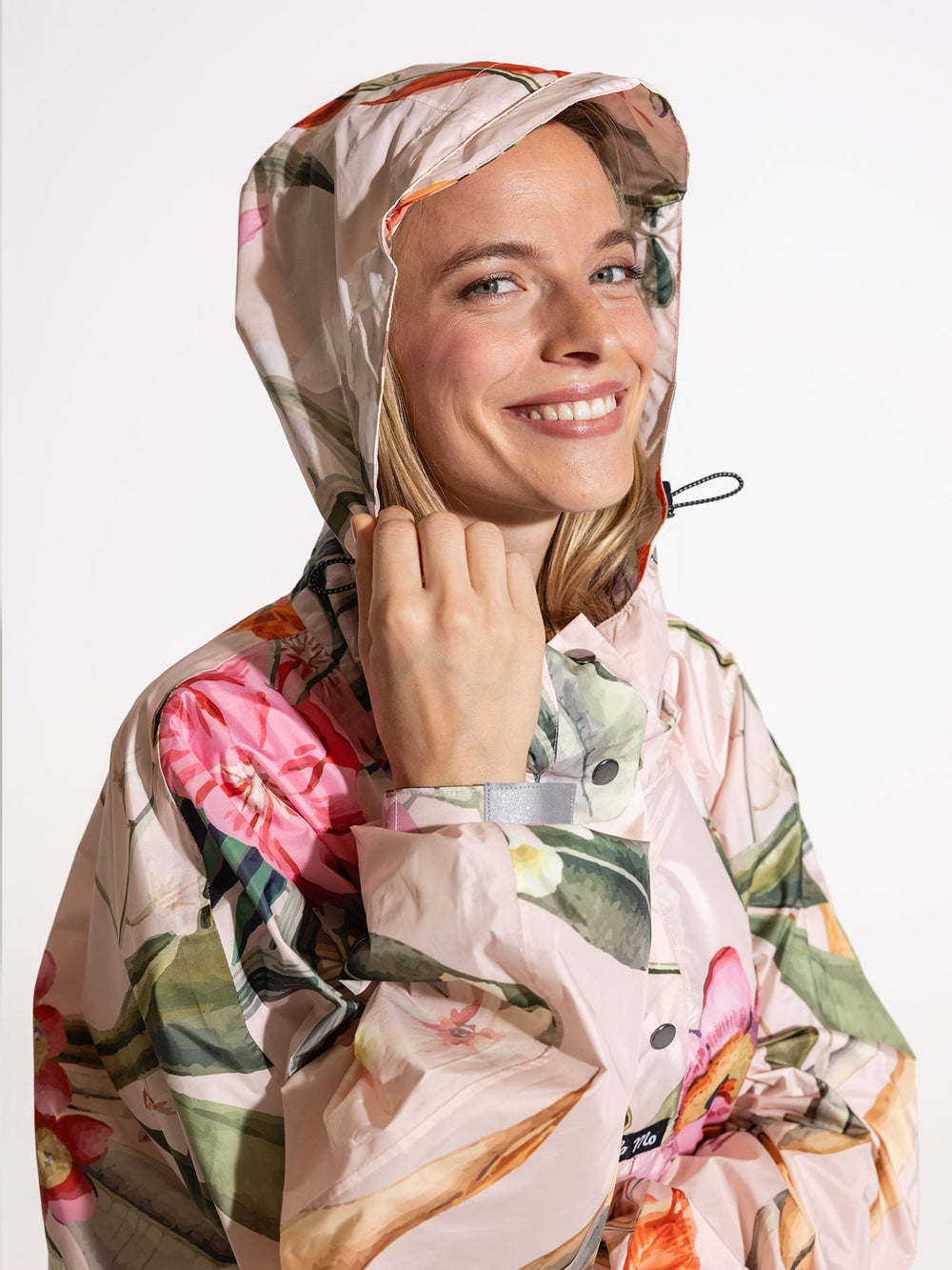 Ela Mo™ Regenponcho | Luxe.  Eine Frau im Regenponcho mit hohem Kragen und Kaputze.
