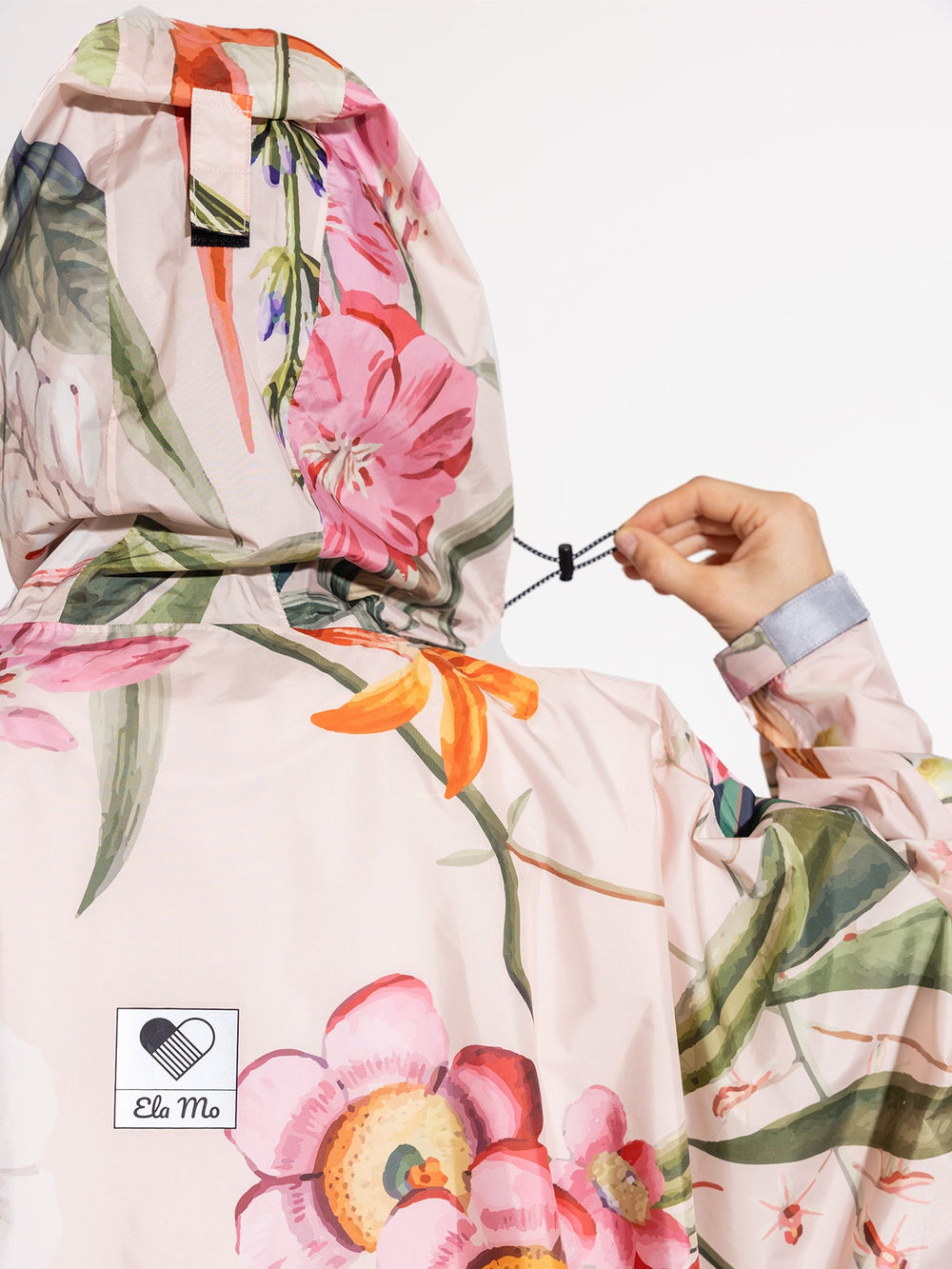 Ela Mo™ Regenponcho | Luxe.  Eine Frau im Regenponcho mit Kaputze. Ansicht von hinten.