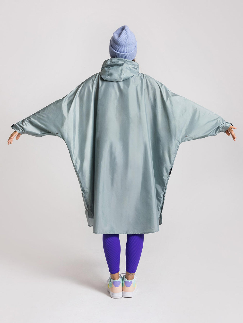 Ela Mo™ Regenponcho | Mint. Frau mit Regenponcho von hinten auf weißem Hintergrund.