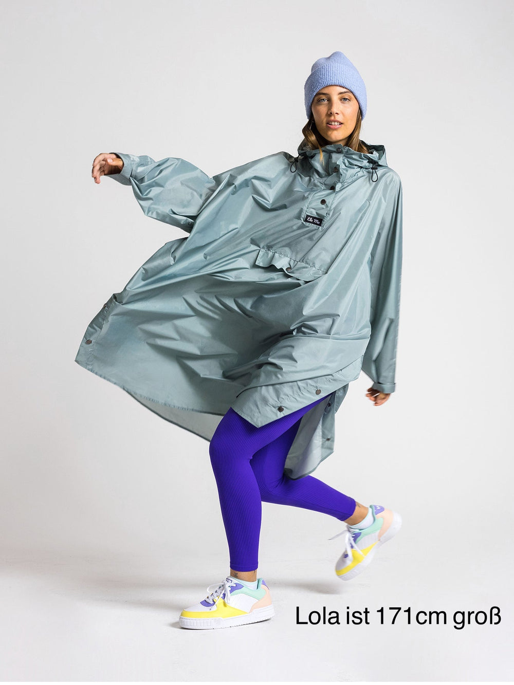 Ela Mo™ Regenponcho | Mint. Eine Frau mit Regenponcho, inklusive Produkt-Höhenangabe.