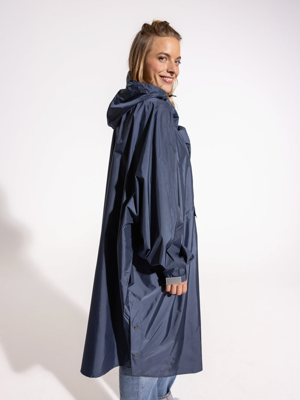 Ela Mo™ Regenponcho | Navy. Seitenansicht der Frau im blauen Regenponcho.