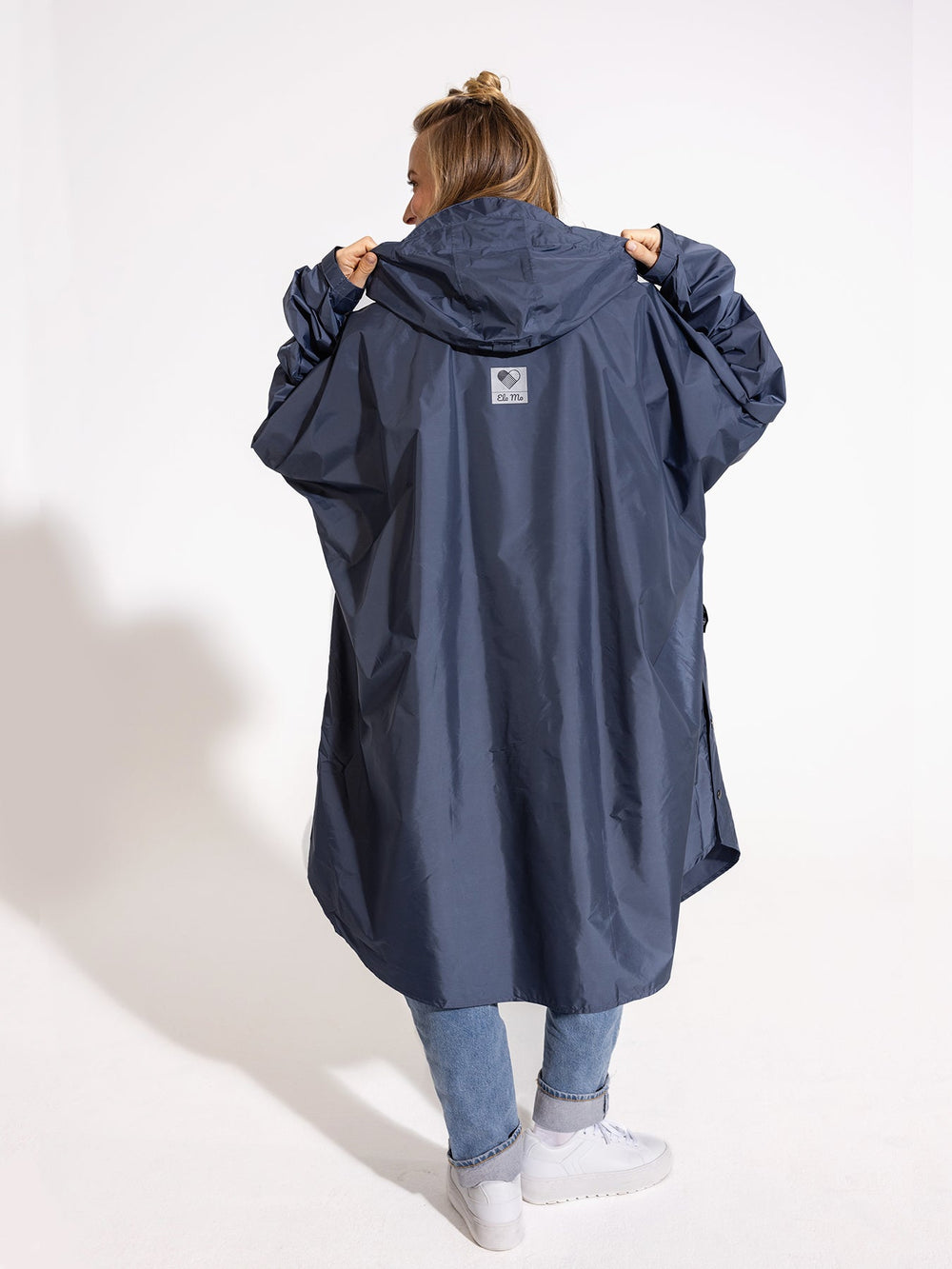 Ela Mo™ Regenponcho | Navy. Eine Frau im Regenponcho, der ausreichend breit ist, auf weißem Hintergrund.