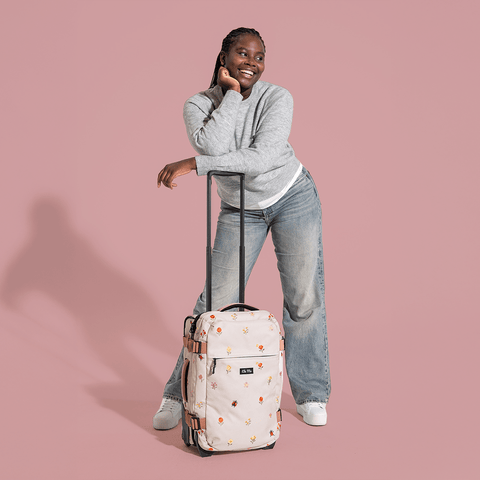 Ela Mo™ Reisetasche mit Rollen 42 Liter | Embroidery Edition Losy. Frau mit der geblümten Tasche und hochgezogenem Griff.
