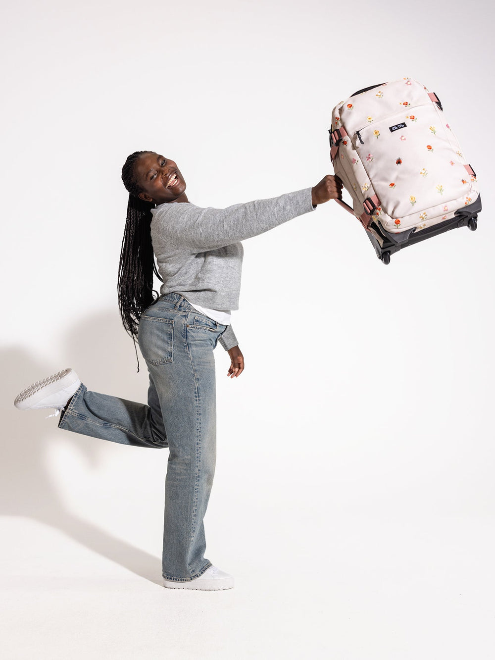 Ela Mo™ Reisetasche mit Rollen 42 Liter | Embroidery Edition Losy. Frau trägt die Tasche ganz leicht am Seitengriff.