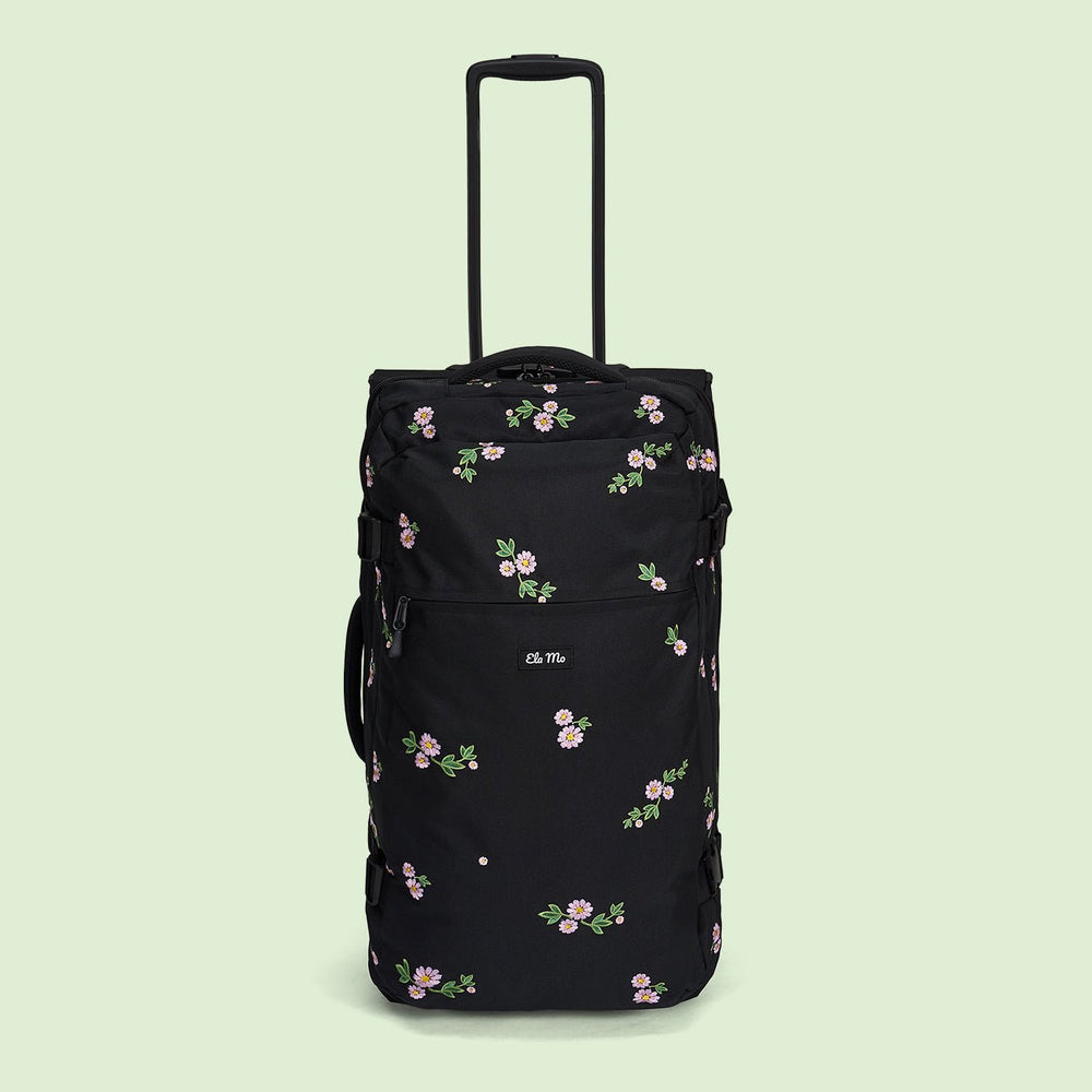 Ela Mo™ Reisetasche mit Rollen 78 Liter | Embroidery Edition Upsy Daisy. Schwarze, geblümte Tasche mit hochgezogenem Griff.