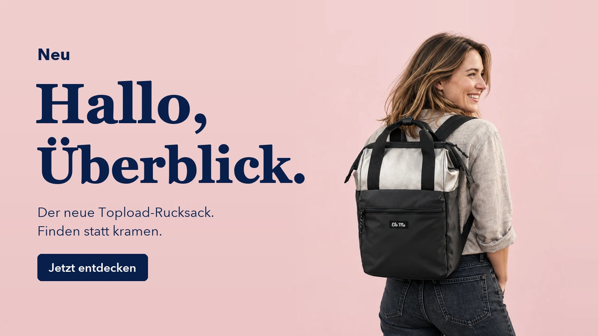 Neu. Hallo, Überblick. Der neue Topload-Rucksack. Finden statt kramen. Jetzt entdecken. Frau mit dem Silver Lining Rucksack vor rosafarbenem Hintergrund.